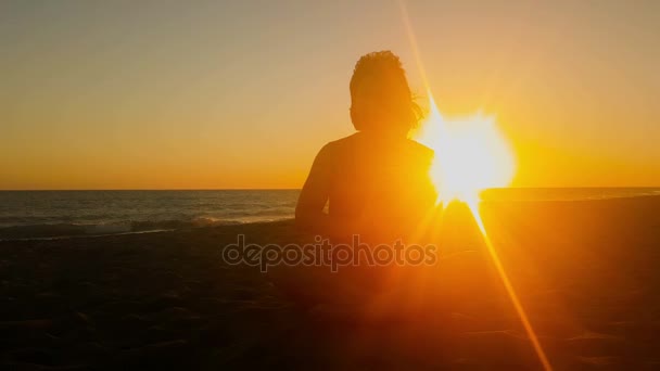 Vrouw doet yoga tegen de zonsondergang. — Stockvideo