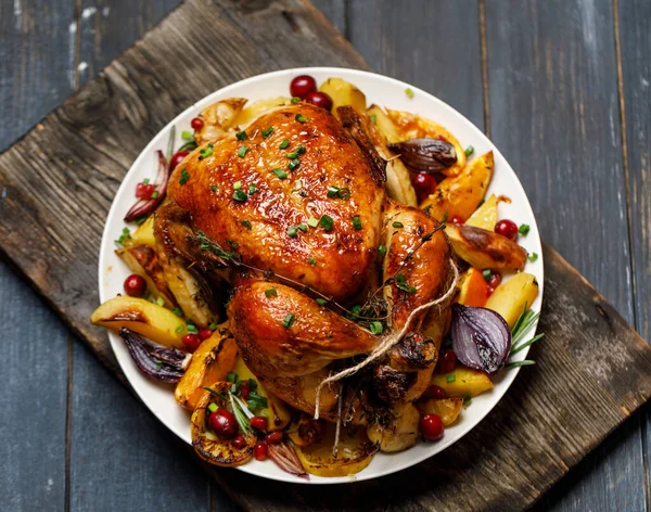 Roast whole chicken with roast vegetables on plate on a table
