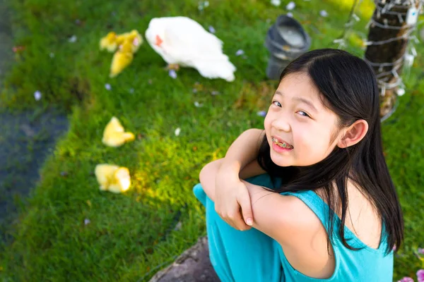 Счастливый азиатский ребенок, сидящий с желтыми утками — стоковое фото