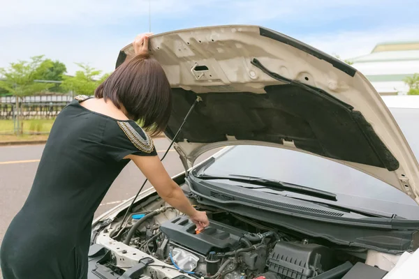 Giovane donna controllando con la riparazione della sua auto rotta . — Foto Stock