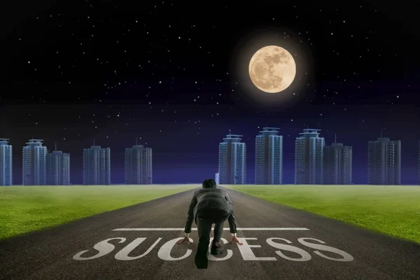 Business man ready to run SUCCESS line in front of city. Night b — Stock Photo, Image