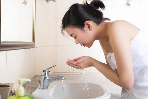 Junge Frau wäscht ihr Gesicht im Badezimmer. — Stockfoto