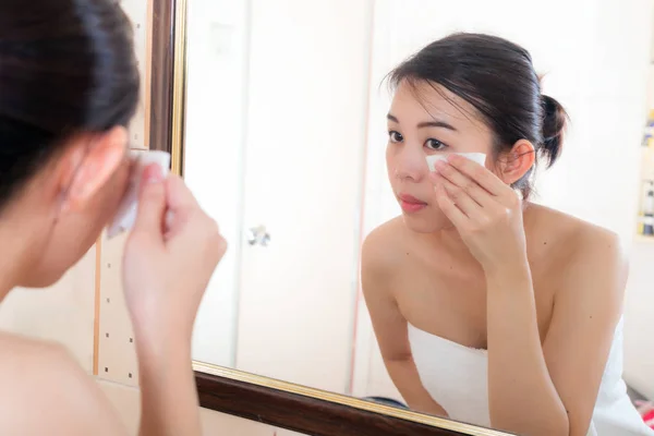 Hermosa mujer quitando el maquillaje de su cara en el baño . — Foto de Stock