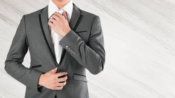 Business man hand holding necktie in grey suite on wooden backgr — Stock Photo, Image