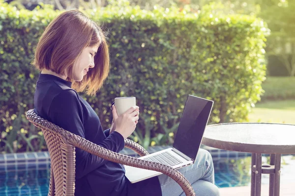 Kahve fincan sıcak tutarak ve dizüstü sabah oynayan eller.