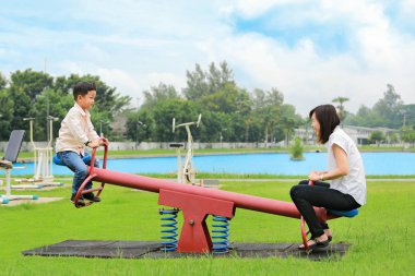 Anne oğluyla tahterevalli parkta oynarken.