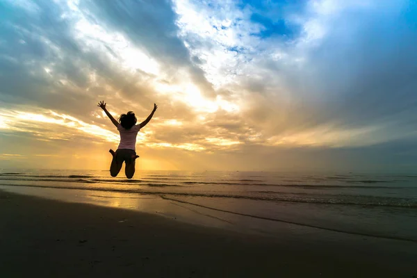 Frau springt bei Sonnenuntergang auf Sand am Meer. Freiheitslebenskonzept — Stockfoto