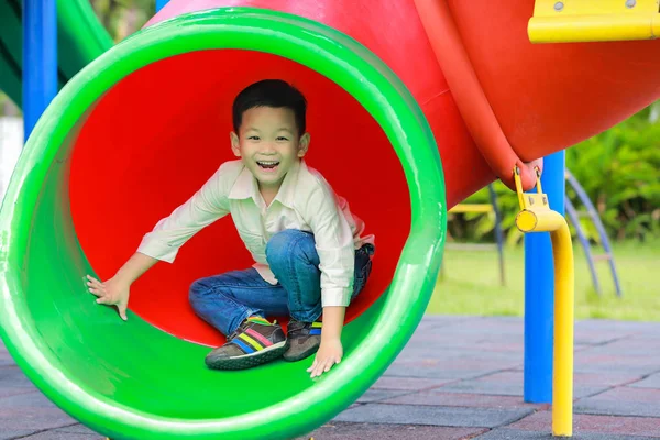 Crianças brincando em um túnel deslizante no parque infantil . — Fotografia de Stock