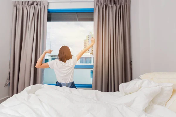 Kvinnan sträcker sig på sängen efter vakna upp, bakifrån. — Stockfoto