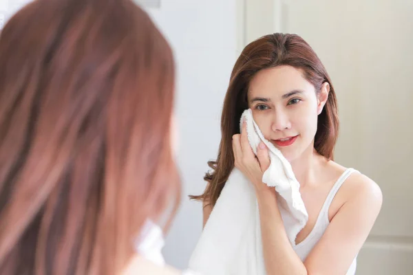 Junge Frau wischt sich im Badezimmer mit Handtuch das Gesicht ab. — Stockfoto