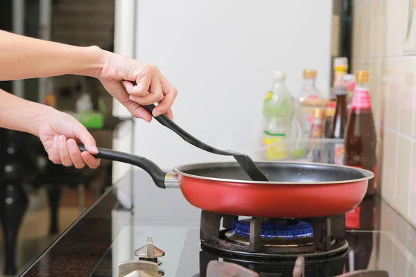 Woman holding a pan in the hand cooking omelette in kitchen. — Stock Photo, Image