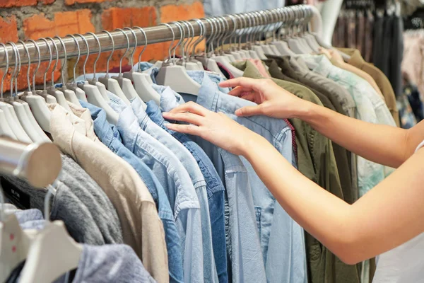 Bir galeride bir raf üzerinde giysiler seçmek eller.