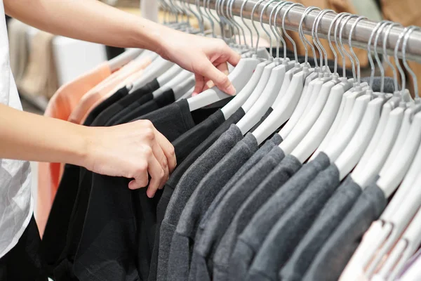 Bir galeride bir raf üzerinde giysiler seçmek eller.