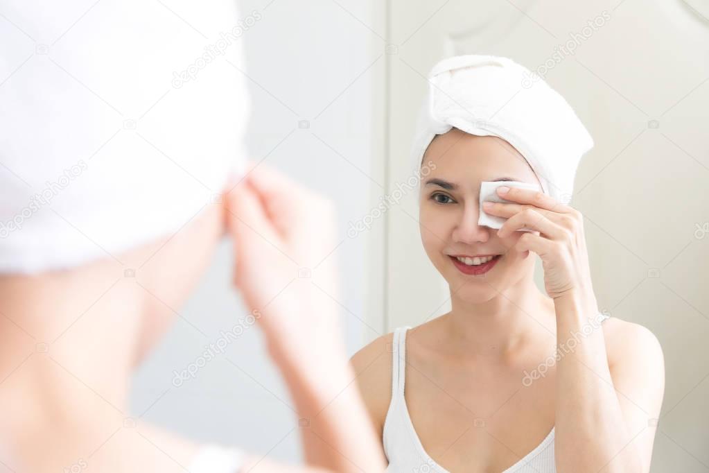 Healthy fresh girl removing makeup from her face with cotton pad
