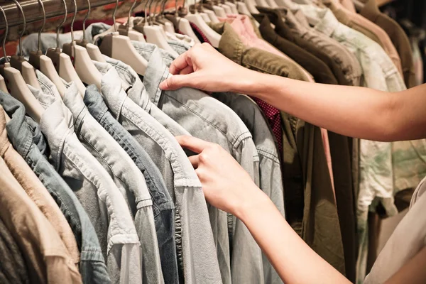 Manos eligiendo la ropa en un estante en una sala de exposición . —  Fotos de Stock