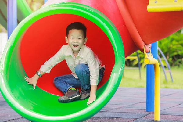 Crianças brincando em um túnel deslizante no parque infantil . — Fotografia de Stock