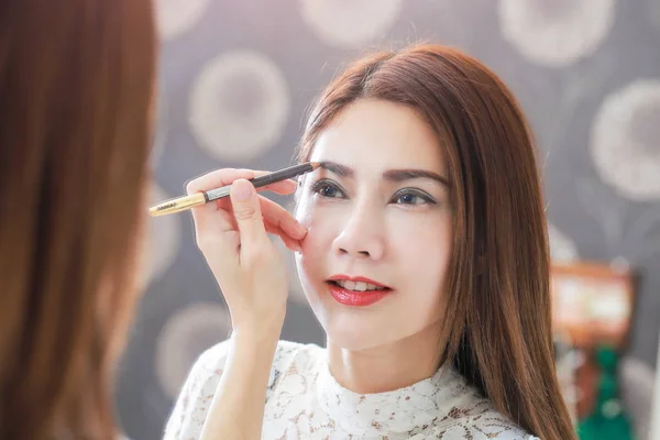 Close up de belo rosto de jovem mulher ficando maquiagem em seu — Fotografia de Stock