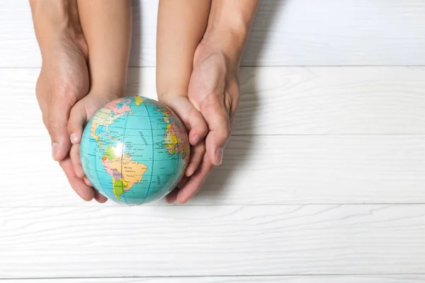 World concept: Two human hands holding global on wooden backgrou — Stock Photo, Image