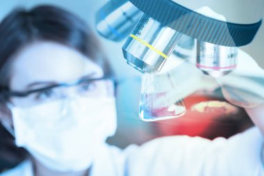 Genç bilim adamı laboratuvarda test tüpü bakarak.