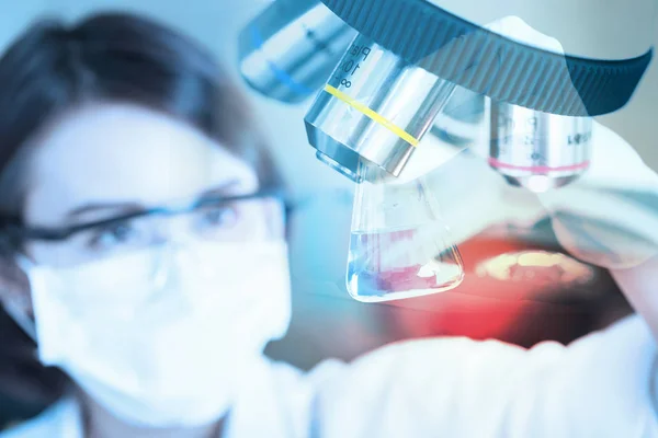 Científico joven mirando el tubo de ensayo en el laboratorio . — Foto de Stock