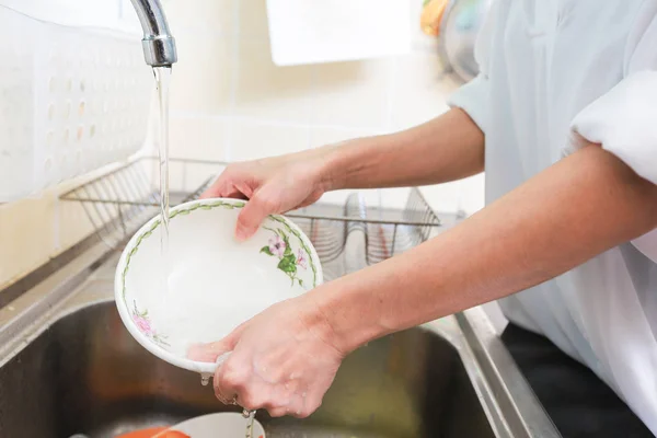 Закройте руки женщины, моющей посуду на кухне . — стоковое фото