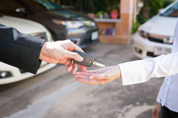 Vendedor que oferece a chave do carro a um cliente no carro usado showroom . — Fotografia de Stock