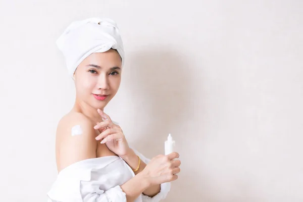 Menina bonita na toalha de banho está aplicando creme em seu ombro . — Fotografia de Stock