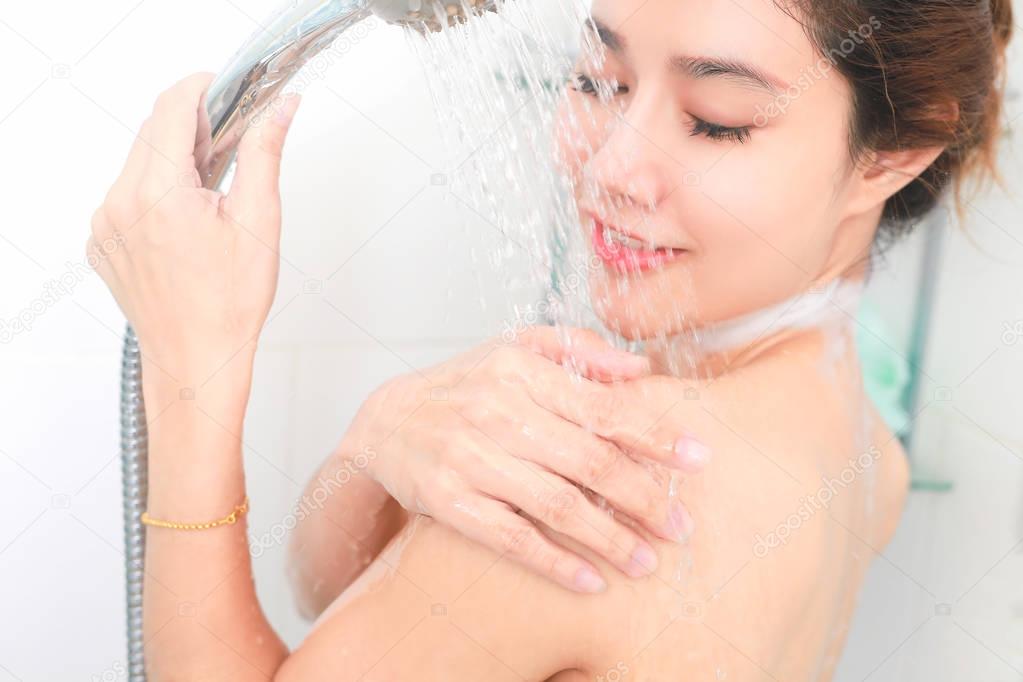 Woman taking a shower enjoying water splashing on her. selective