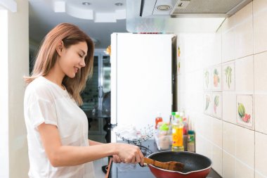 Genç Asyalı kadın bir mutfakta omlet yapmak.