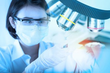 Genç bilim adamı laboratuvarda test tüpü bakarak.