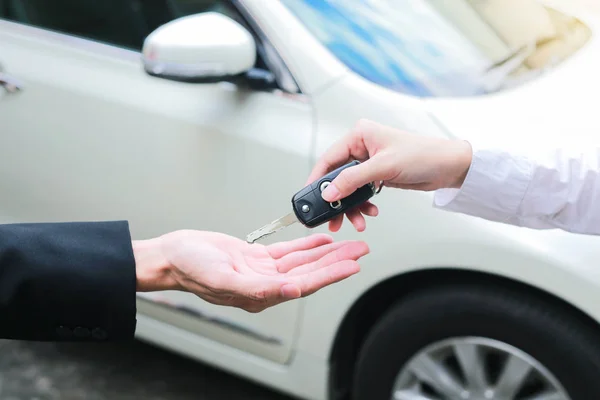Fechar-se de um proprietário do carro fêmea dando chaves do carro da venda do carro — Fotografia de Stock