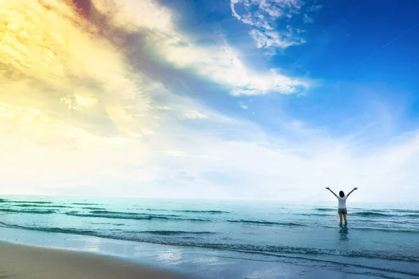 Glückliche Frau, die auf dem Sand des Meeres steht und Hand in Hand zum Himmel zeigt. — Stockfoto