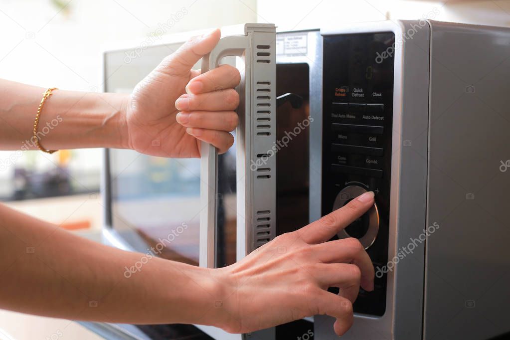 Woman's Hands Closing Microwave Oven Door And Preparing Food in 