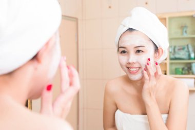 Güzel genç bir kadının banyo havlusuyla krem sürdüğü yakın plan.