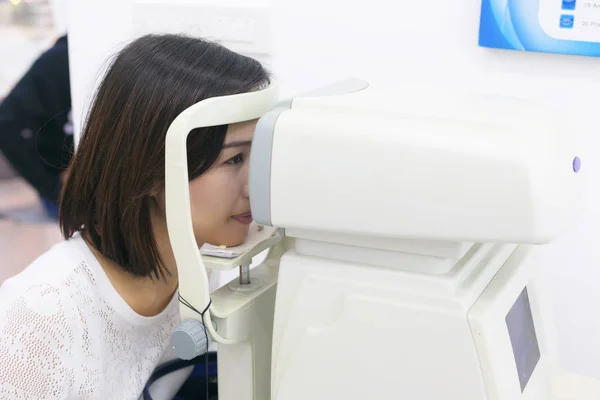 Woman doing eye test with optometrist machine in eye sight clini — Stock Photo, Image