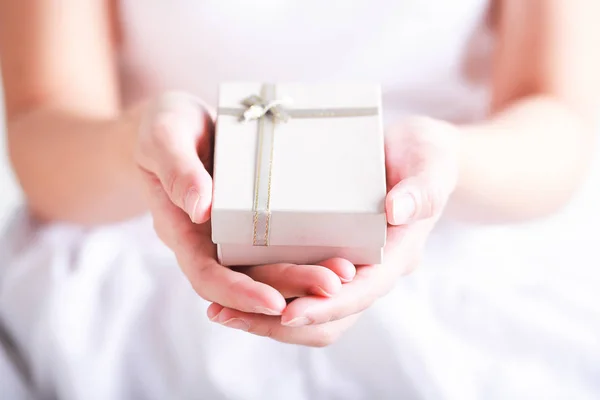 Close up of female hands holding a small gift wrapped with ribbo — Stock Photo, Image