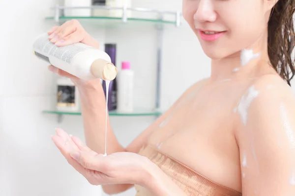 Woman in bath towel is applying cream on her hand while standing — Stock Photo, Image