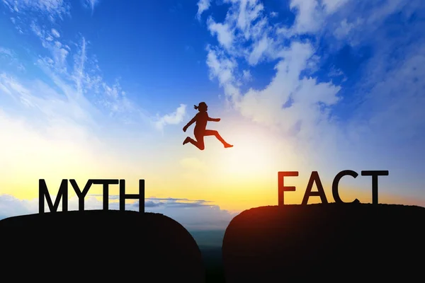 Woman jump through the gap between Myth to Fact on sunset. — Stock Photo, Image