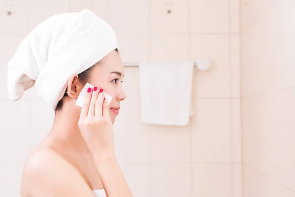 Hermosa mujer aplicando crema cosmética en el baño . — Foto de Stock