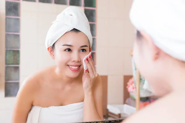 Schöne Frau entfernt Make-up aus ihrem Gesicht im Badezimmer. — Stockfoto