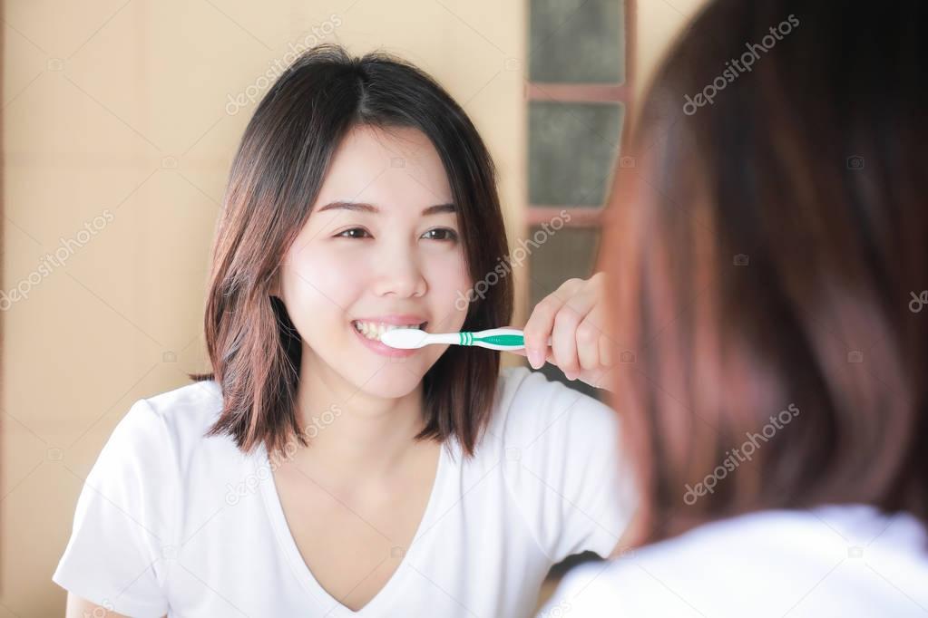 Young woman brushing her teeth at mirror. After awakening
