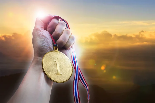 Empresário mão segurando medalha de moeda de ouro na colina . — Fotografia de Stock