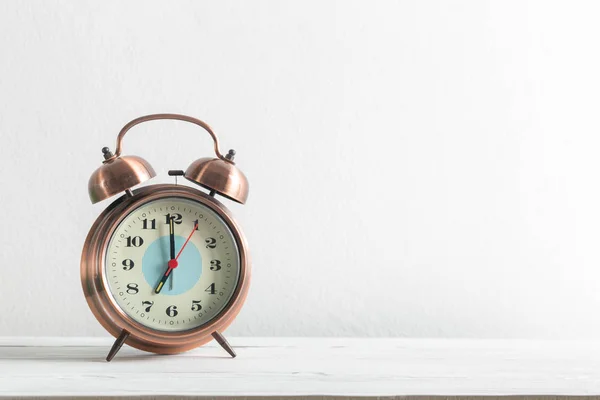 Reloj despertador en una pared blanca y estante de madera . — Foto de Stock