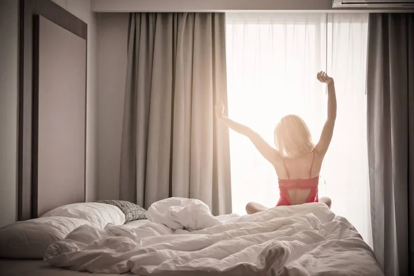 Mulher que se estende perto da cama depois de acordar com o nascer do sol na manhã — Fotografia de Stock