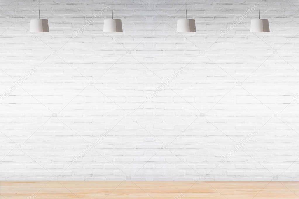 White brick wall in room with wooden floor with lamps.