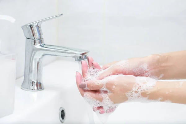 Se laver les mains avec du savon sous le robinet avec de l'eau. — Photo