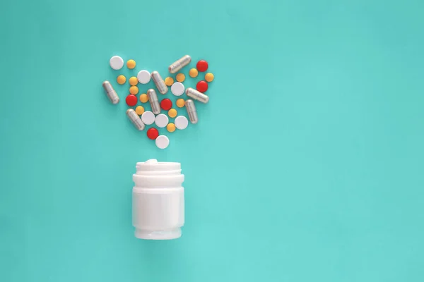 Таблетки, що виливаються з пляшки таблеток і ізольовані на зеленому фоні — стокове фото