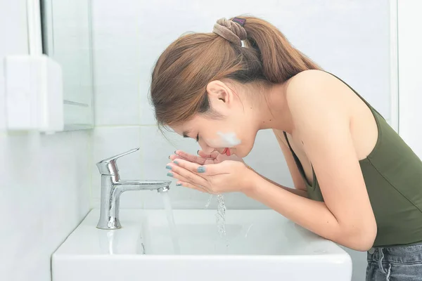 Mulher bonita lavando seu rosto salpicando água em um banho — Fotografia de Stock