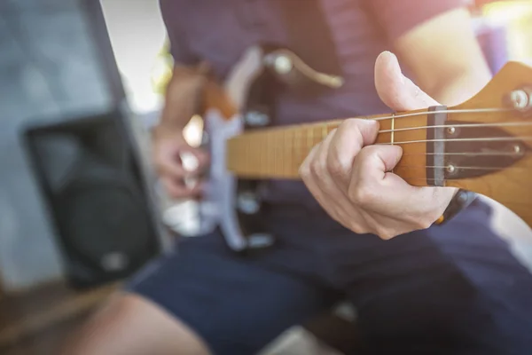 Κοντινό πλάνο Τα χέρια του ανθρώπου παίζουν ακουστική κιθάρα με φωτοβολίδα φωτός. — Φωτογραφία Αρχείου