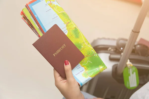 Pasaporte de mano en primer plano y mapa con equipaje . — Foto de Stock